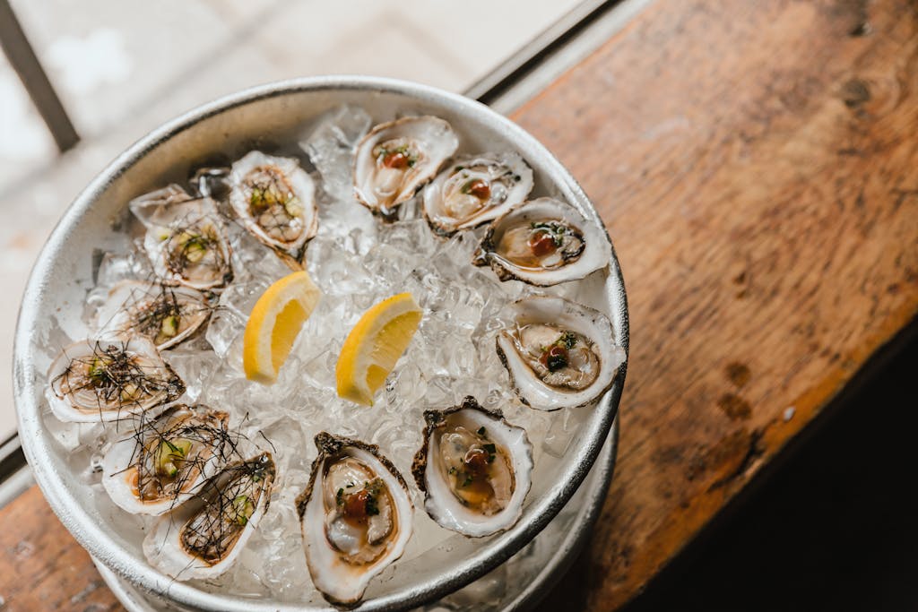 A high-angle view of fresh oysters on crushed ice with lemon slices, ready to eat.