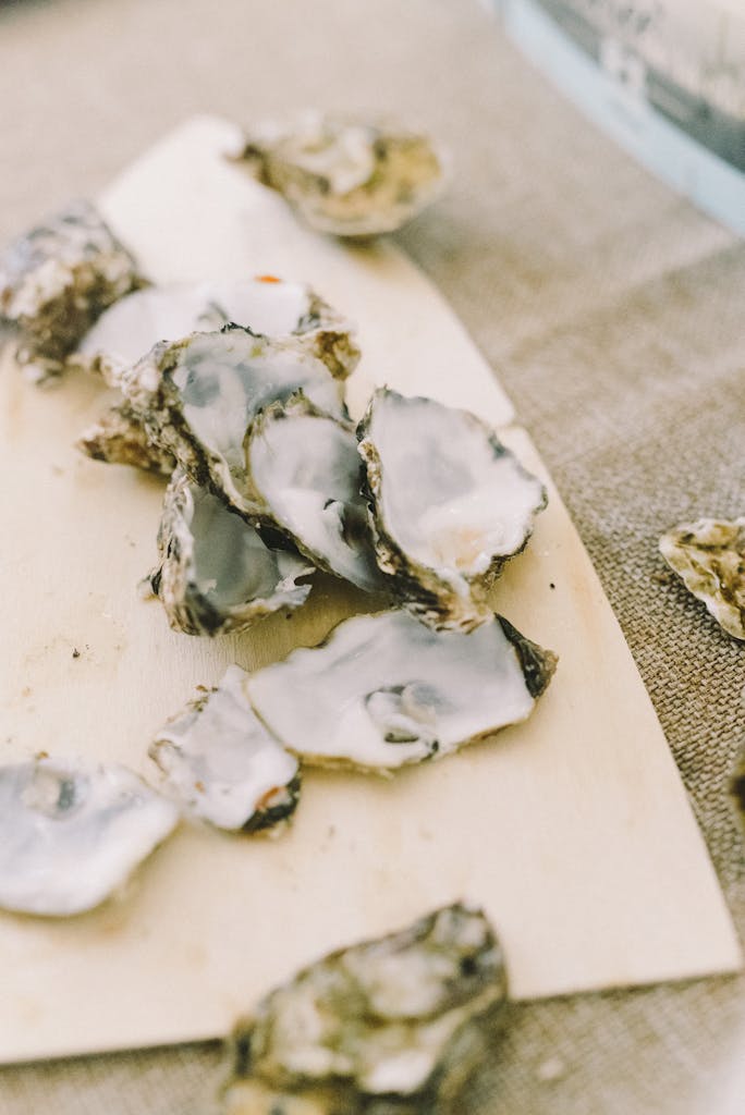 Close-up of freshly shucked oysters on a wooden board, showcasing their natural textures.