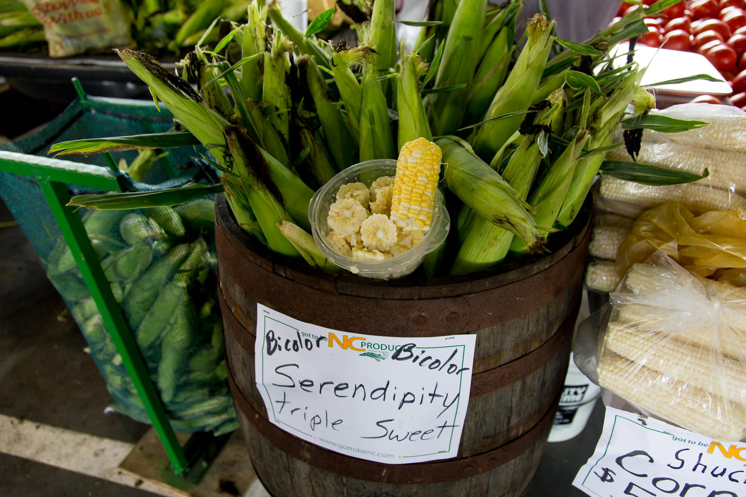 Vibrant bicolor corn displayed in a rustic barrel, showcasing freshness at a North Carolina market.